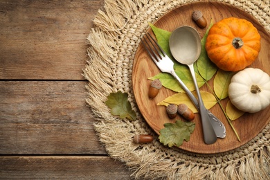 Seasonal table setting with pumpkins and other autumn decor on wooden background, flat lay. Space for text