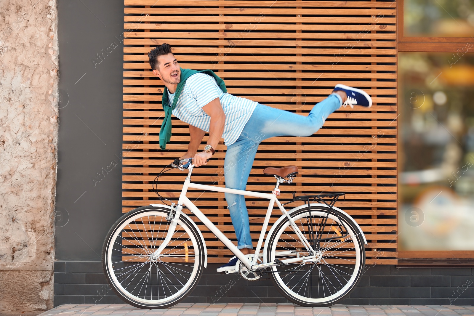 Photo of Handsome young hipster man with bicycle near wooden wall outdoors