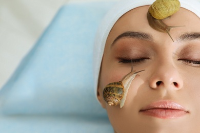 Young woman receiving snail facial massage in spa salon, closeup. Space for text