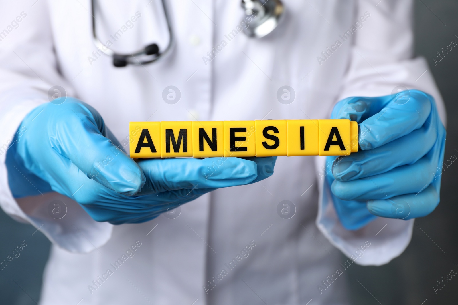 Photo of Doctor holding yellow cubes with word Amnesia, closeup