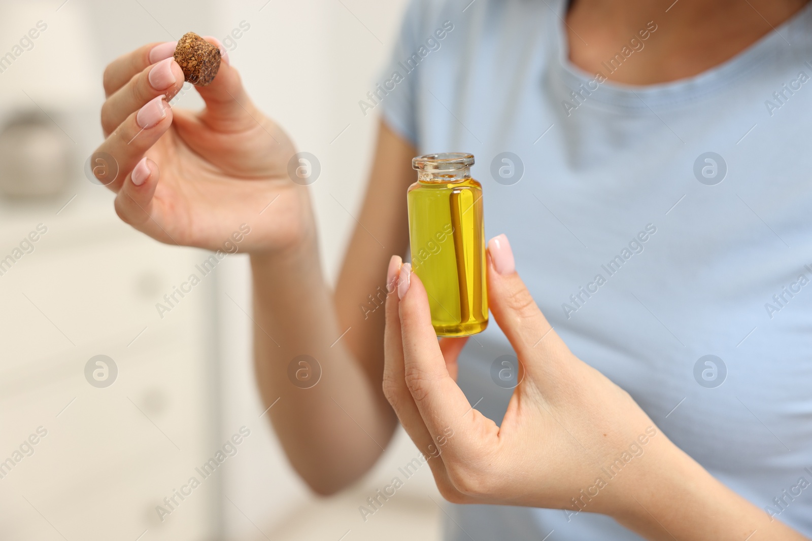 Photo of Aromatherapy. Woman with bottle of essential oil on light background, closeup