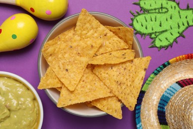 Nachos chips, maracas, guacamole, Mexican sombrero hat and paper cactus on purple background, flat lay