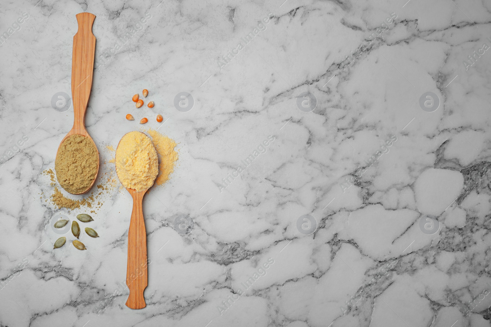 Photo of Spoons with different types of flour on marble background