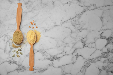 Photo of Spoons with different types of flour on marble background