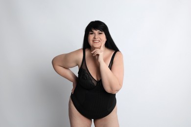 Photo of Beautiful overweight woman in black underwear on light background. Plus-size model