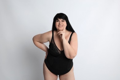 Beautiful overweight woman in black underwear on light background. Plus-size model