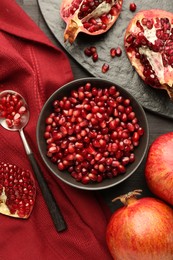 Photo of Tasty ripe pomegranates and grains on dark wooden table, flat lay