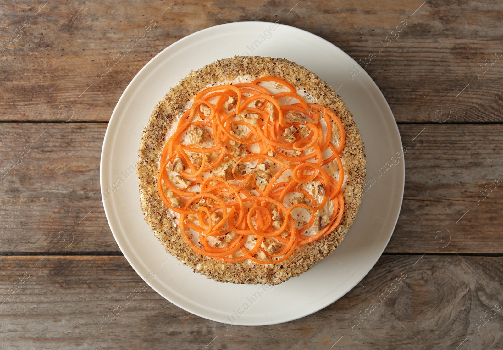 Photo of Dish with delicious carrot cake on wooden background, top view