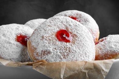Photo of Delicious donuts with jelly and powdered sugar in bowl, closeup