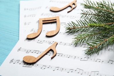 Photo of Christmas tree branch, notes and music sheets on blue wooden table