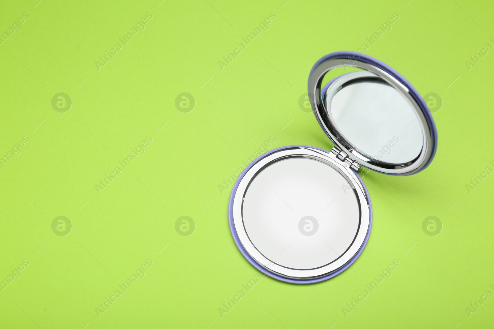 Photo of Stylish cosmetic pocket mirror on light green background, top view. Space for text
