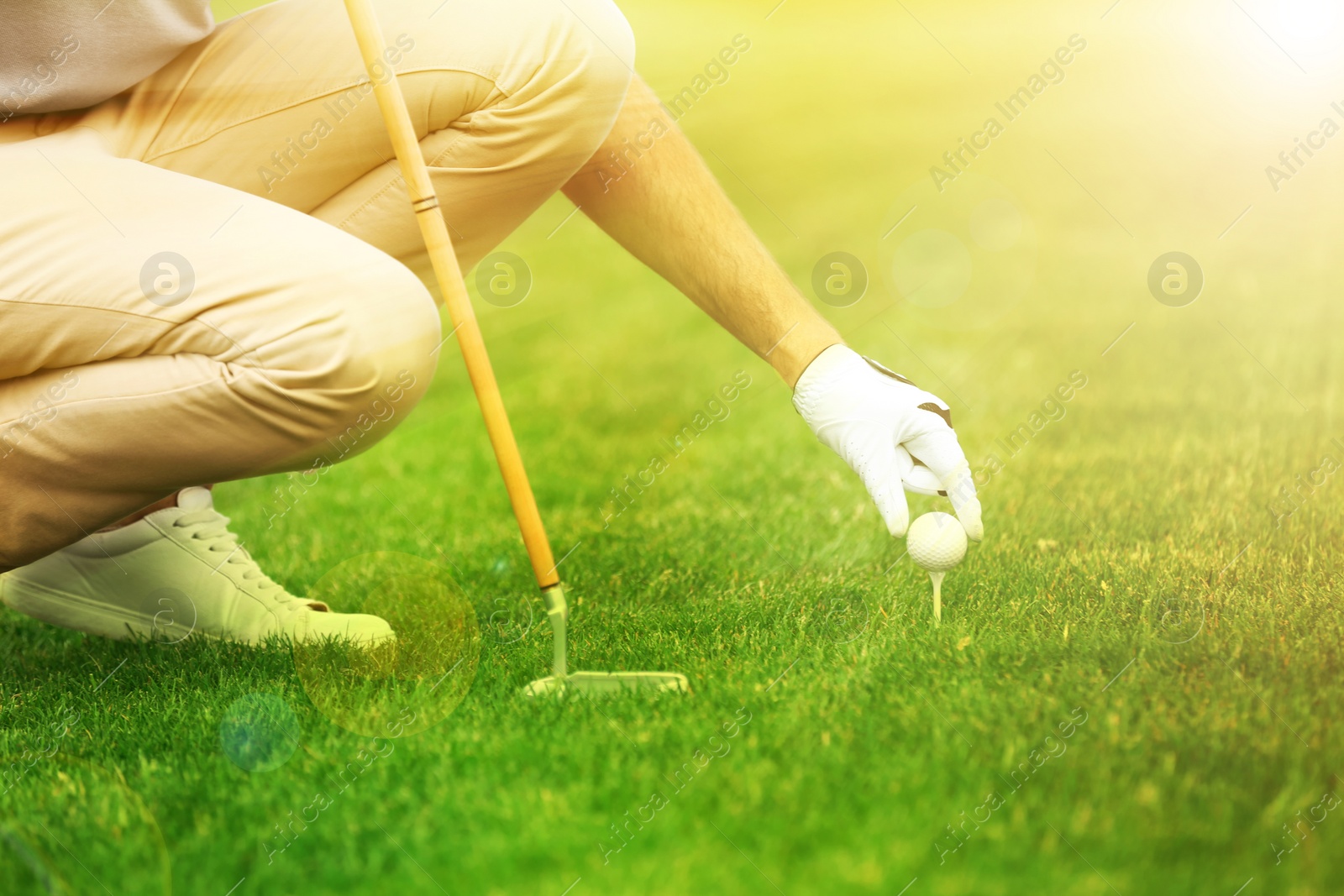 Image of Man playing golf in park on sunny day