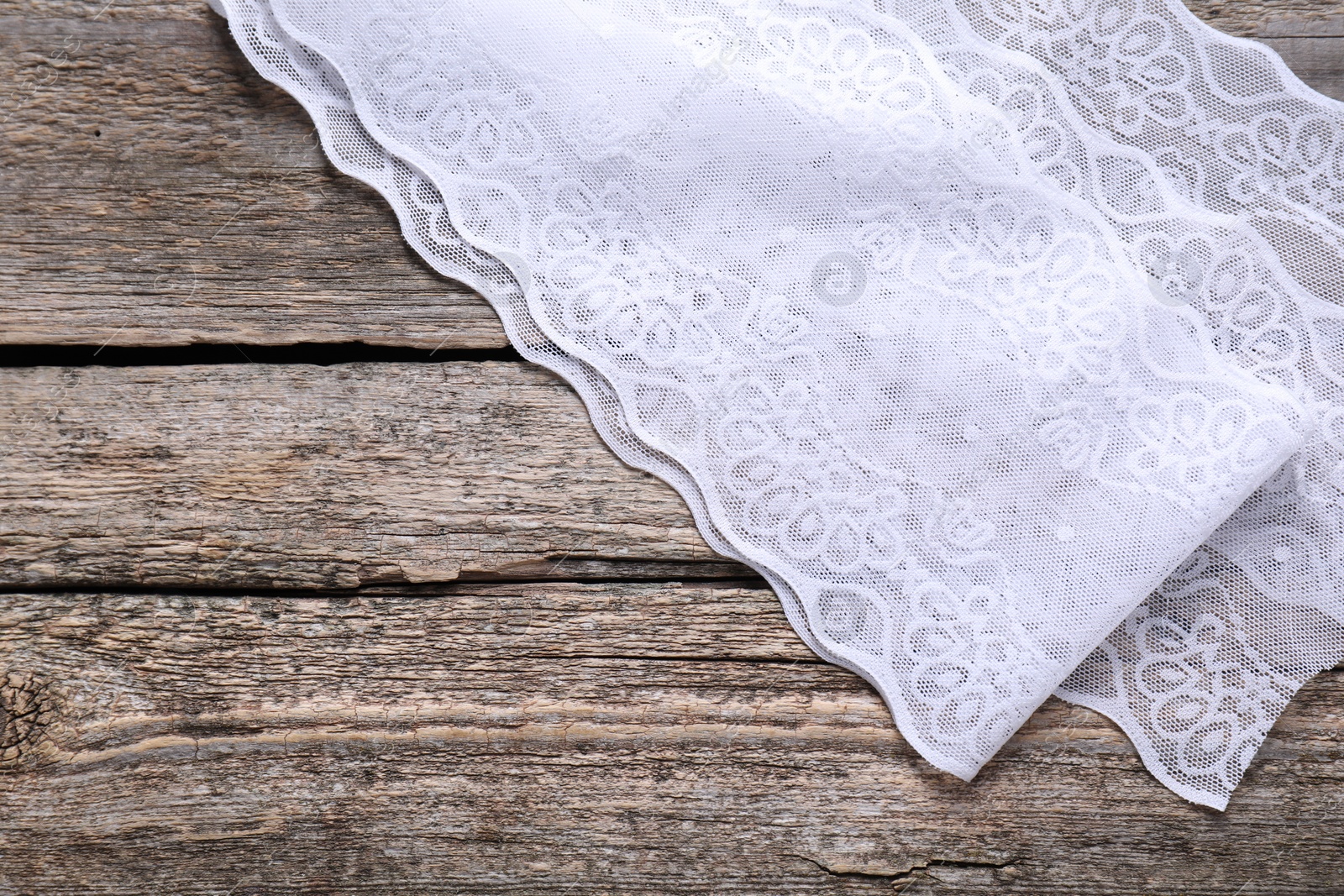 Photo of White lace on wooden table, top view. Space for text