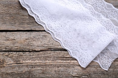 White lace on wooden table, top view. Space for text