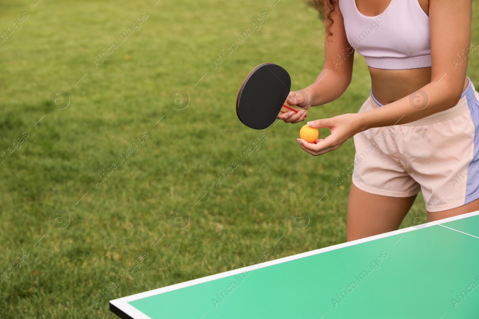 Photo of African-American woman playing ping pong outdoors, closeup