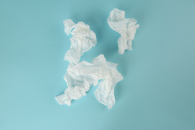 Used paper tissues on light blue background, flat lay