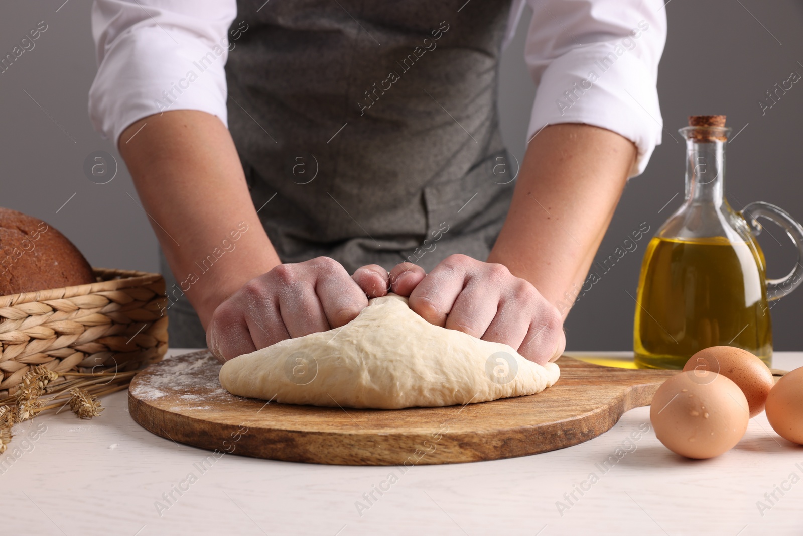 Photo of Man kneading dough at table near grey wall, closeup