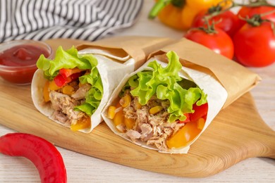 Photo of Delicious tortilla wraps with tuna on white wooden table