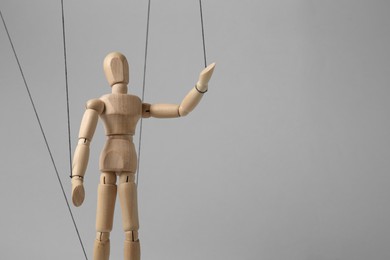 One wooden puppet with strings on light grey background. Space for text