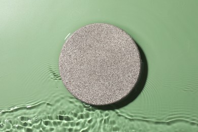 Photo of Presentation for product. Stone podium in water on green background, top view