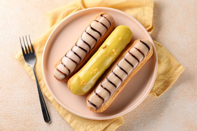 Photo of Different tasty glazed eclairs served on color textured table, top view