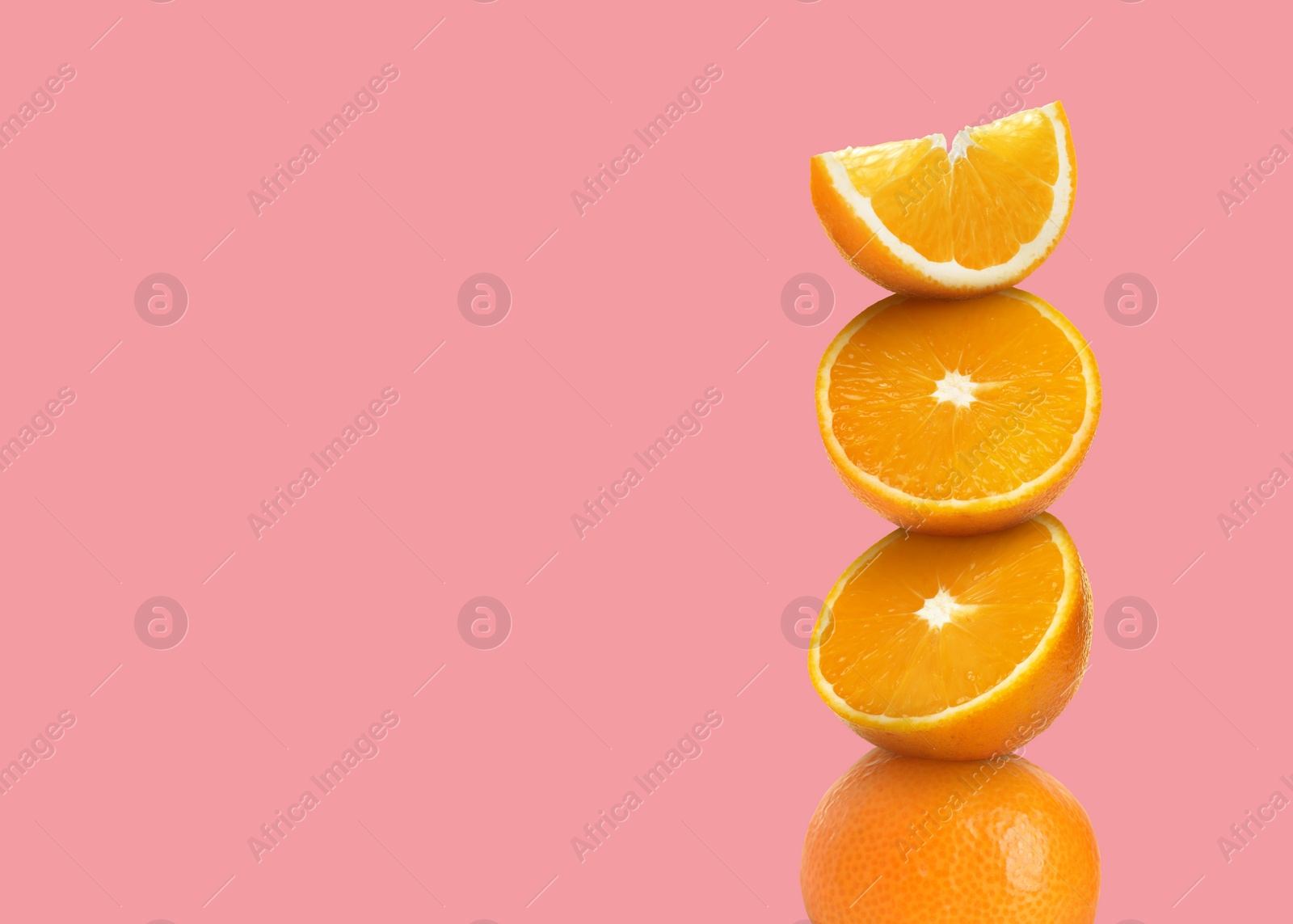 Image of Stacked cut and whole oranges on pink background, space for text