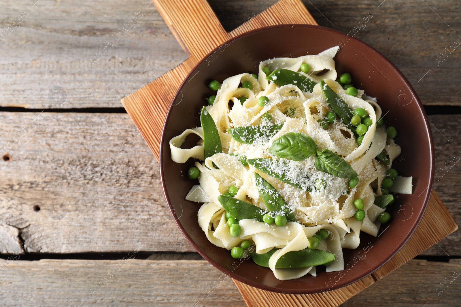 Photo of Delicious pasta with green peas and cheese on wooden table, top view. Space for text