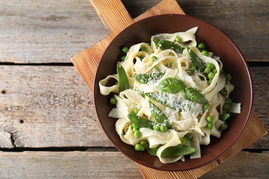 Photo of Delicious pasta with green peas and cheese on wooden table, top view. Space for text