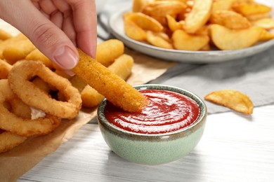 Photo of Woman dipping cheese stick into bowl with tasty ketchup at white table, closeup