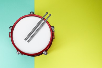 Drum and sticks on color background, top view with space for text. Percussion musical instrument