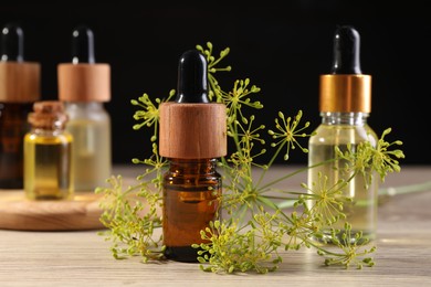 Photo of Bottles of essential oil and fresh dill on wooden table