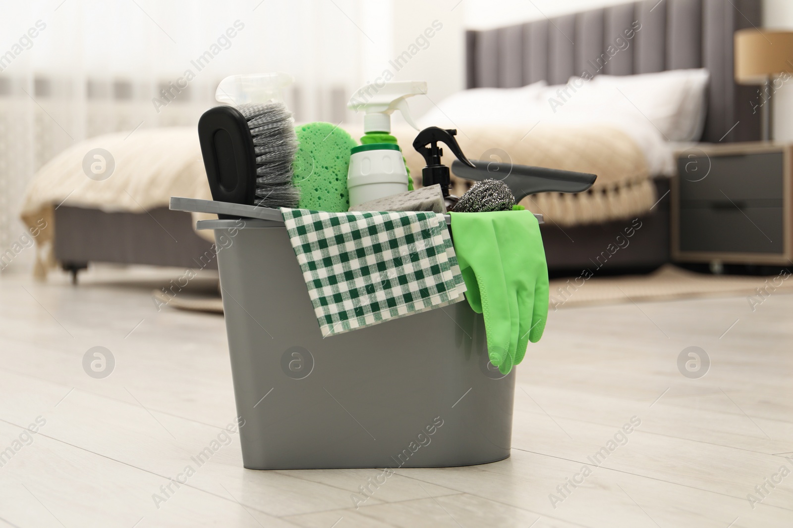 Photo of Different cleaning supplies in bucket on floor at home