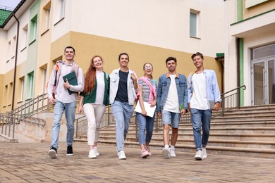 Photo of Group of happy young students walking together outdoors