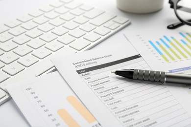 Photo of Accounting documents, pen and computer keyboard on white table, closeup