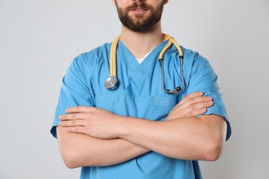 Doctor or medical assistant (male nurse) with stethoscope on light grey background, closeup