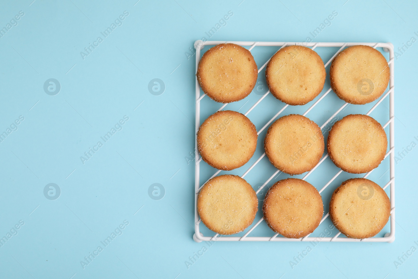 Photo of Tasty sweet sugar cookies on light blue background, top view. Space for text