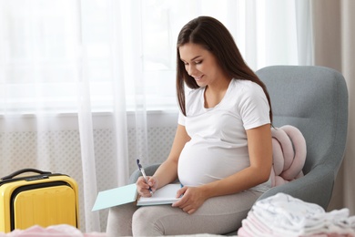 Photo of Pregnant woman writing packing list for maternity hospital at home
