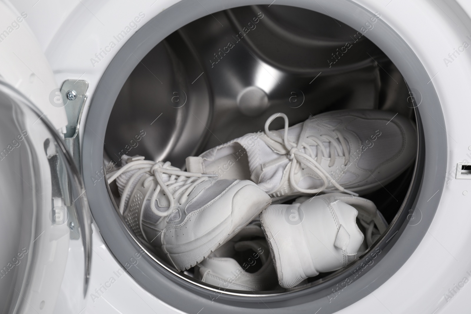 Photo of Stylish clean sneakers inside modern washing machine