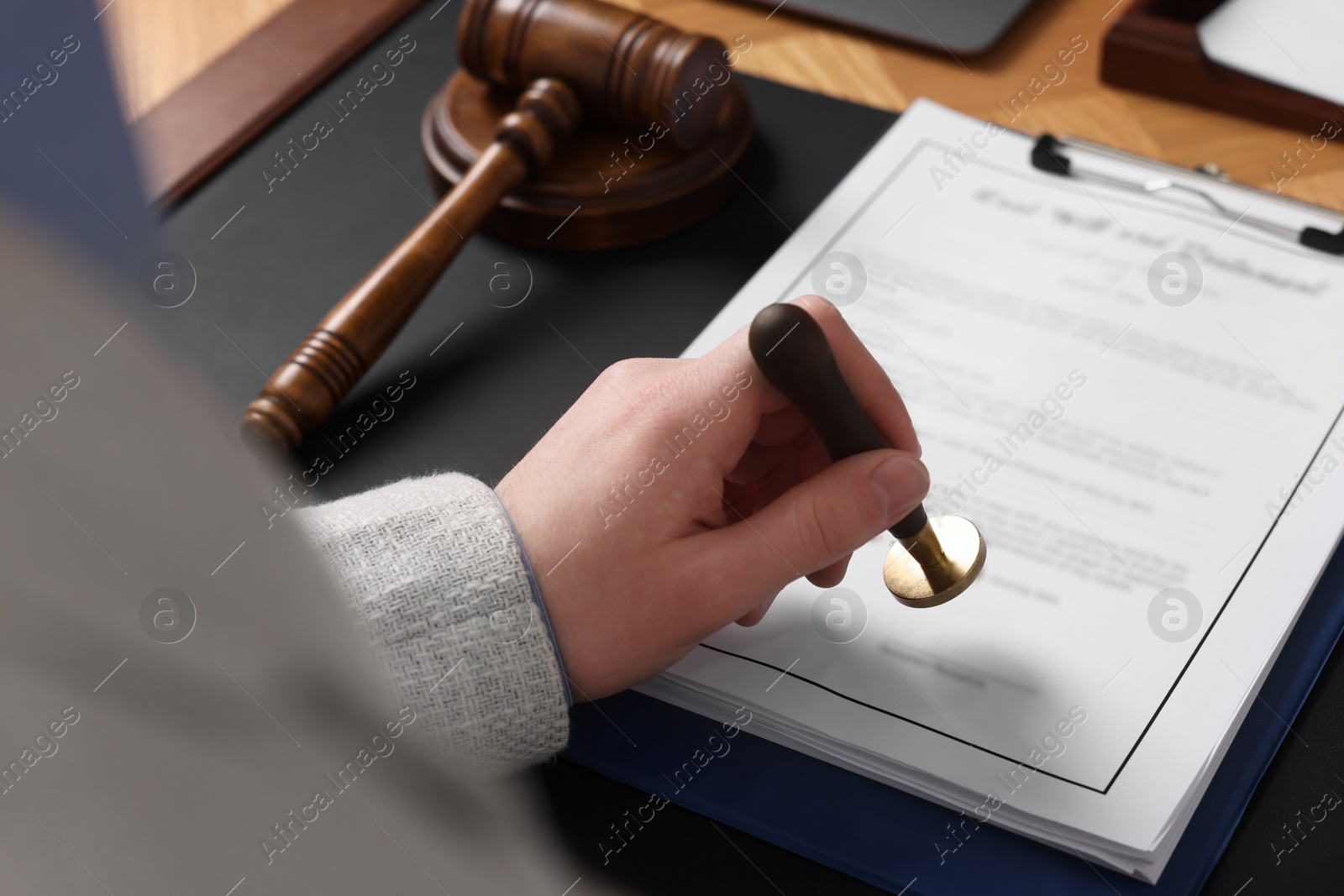 Photo of Notary stamping document at table, closeup view