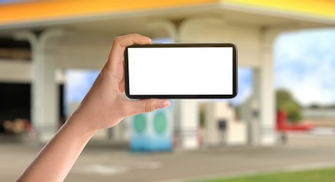 Image of Woman paying for refueling via smartphone at gas station, closeup. Device with empty screen