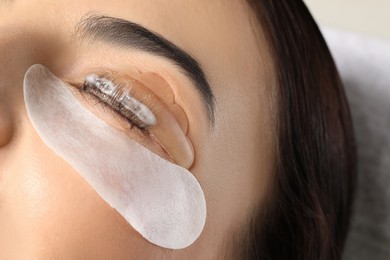 Photo of Young woman undergoing eyelash lamination, closeup. Professional service