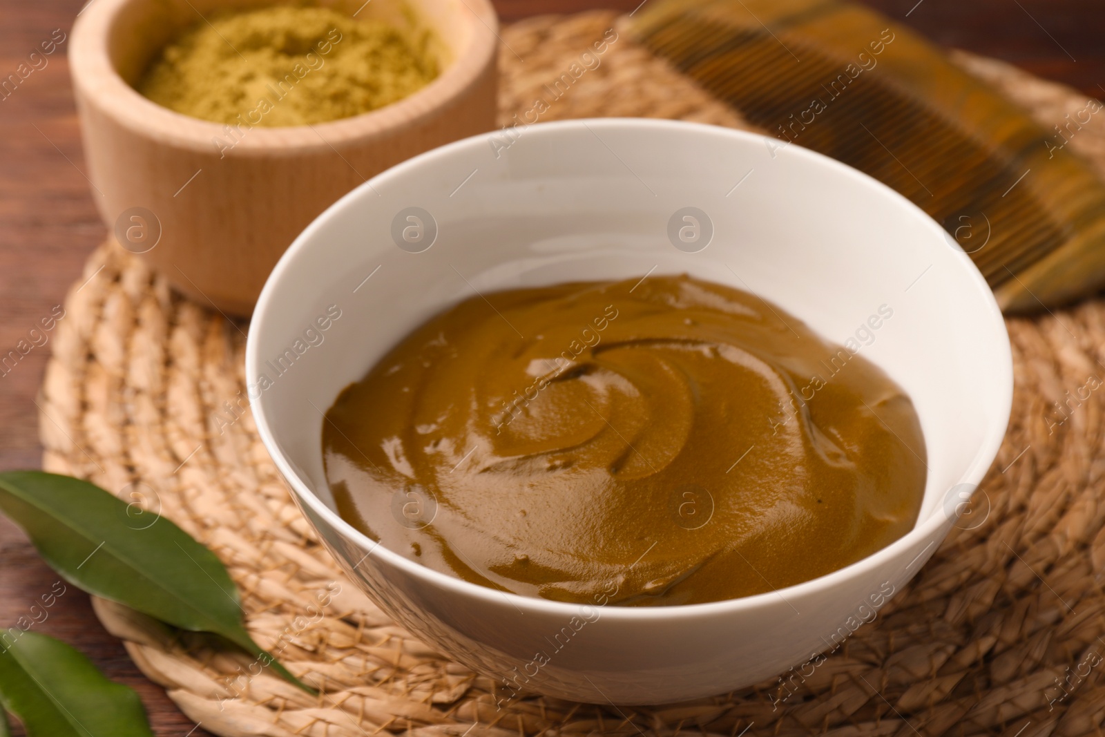 Photo of Bowl of henna cream on wooden table, closeup. Natural hair coloring