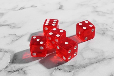 Photo of Many red game dices on white marble table, closeup