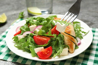 Delicious salad with meat, arugula and vegetables on grey table, closeup