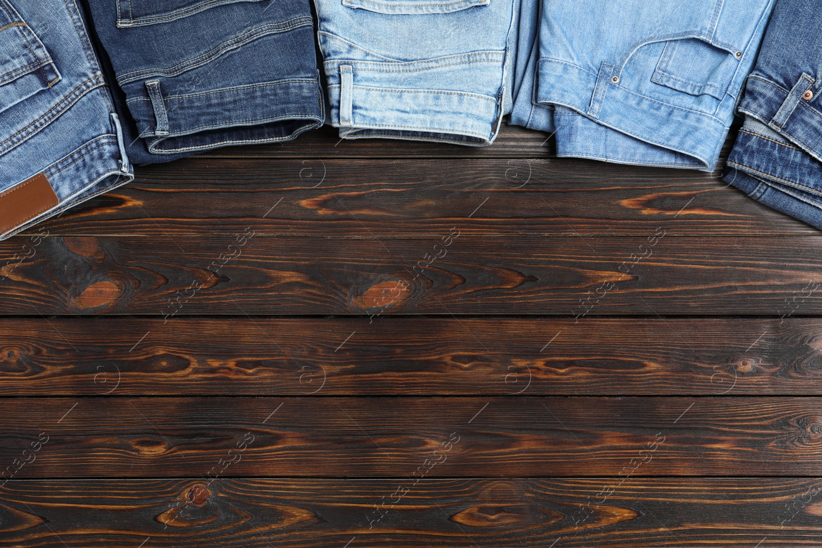 Photo of Collection of stylish jeans on wooden background, flat lay. Space for text