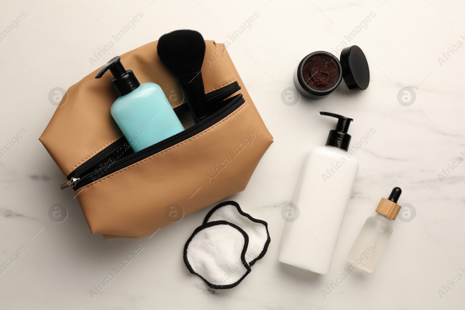 Photo of Preparation for spa. Compact toiletry bag and different cosmetic products on white marble table, flat lay