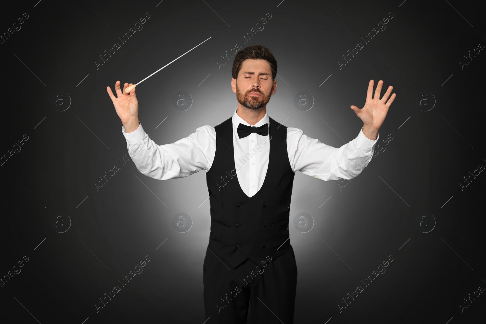 Photo of Professional conductor with baton on black background