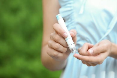 Photo of Woman using lancet pen on blurred background. Diabetes control