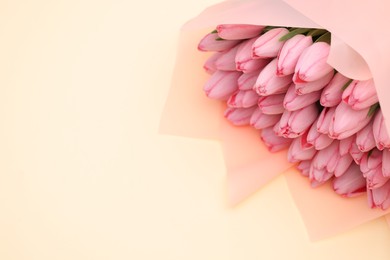 Bouquet of beautiful pink tulips on beige background, above view. Space for text