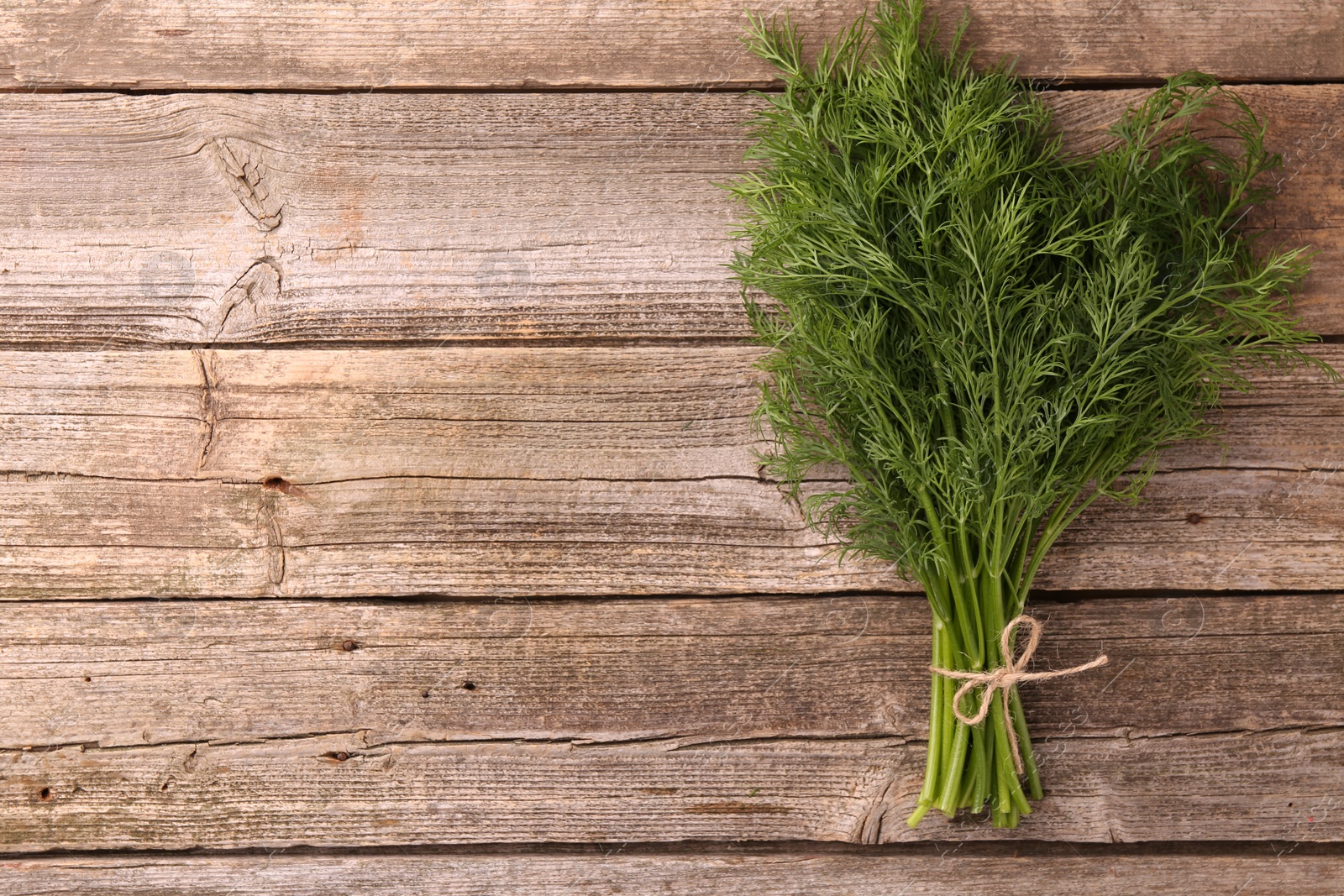 Photo of Bunch of fresh dill on wooden table, top view. Space for text